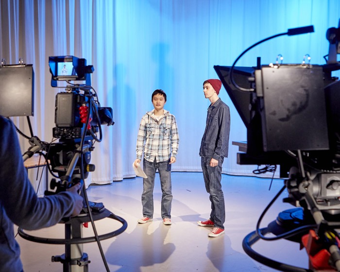 Two students presenting in front of a camera in a television studio