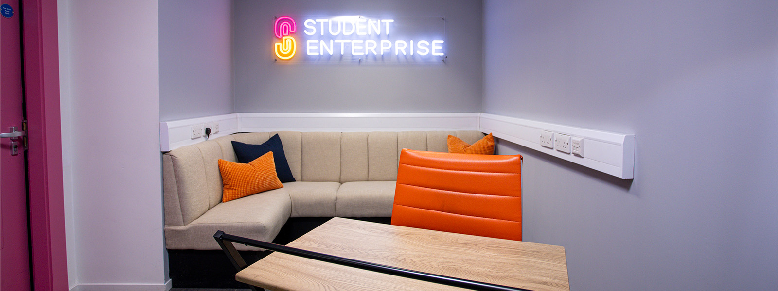 A sofa and a table behind a student enterprise sign