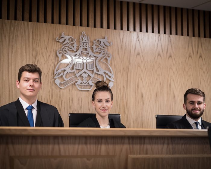 Law students sitting at a judge's bench in the Moot Court