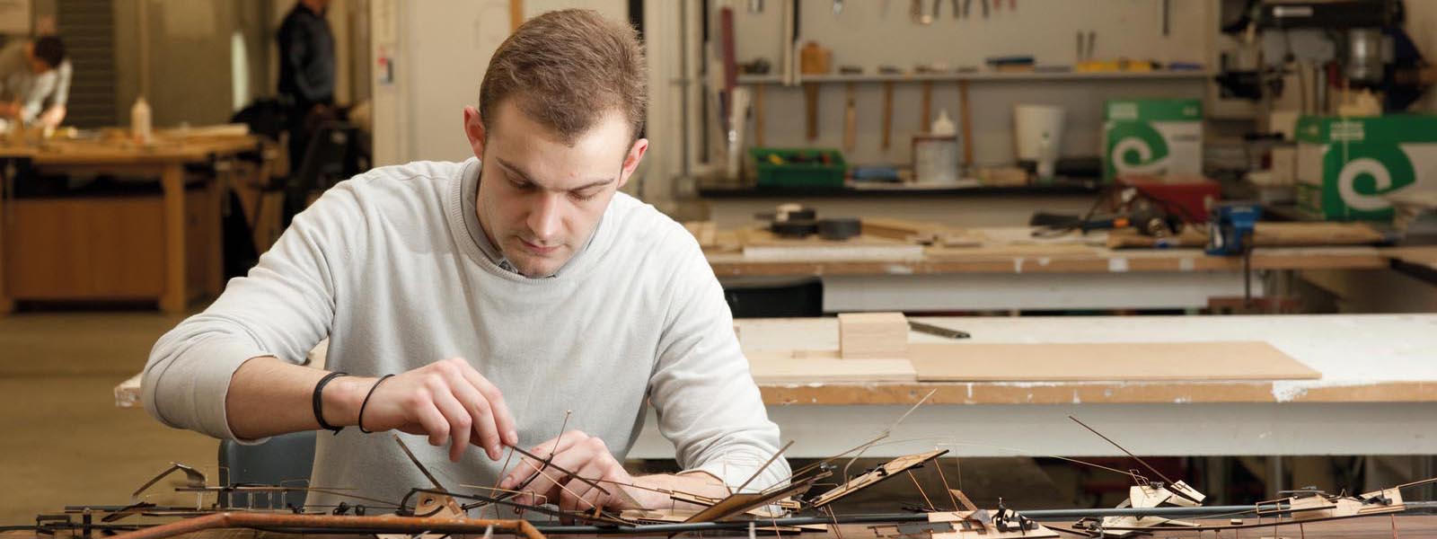 Male student working on a model in the workshop