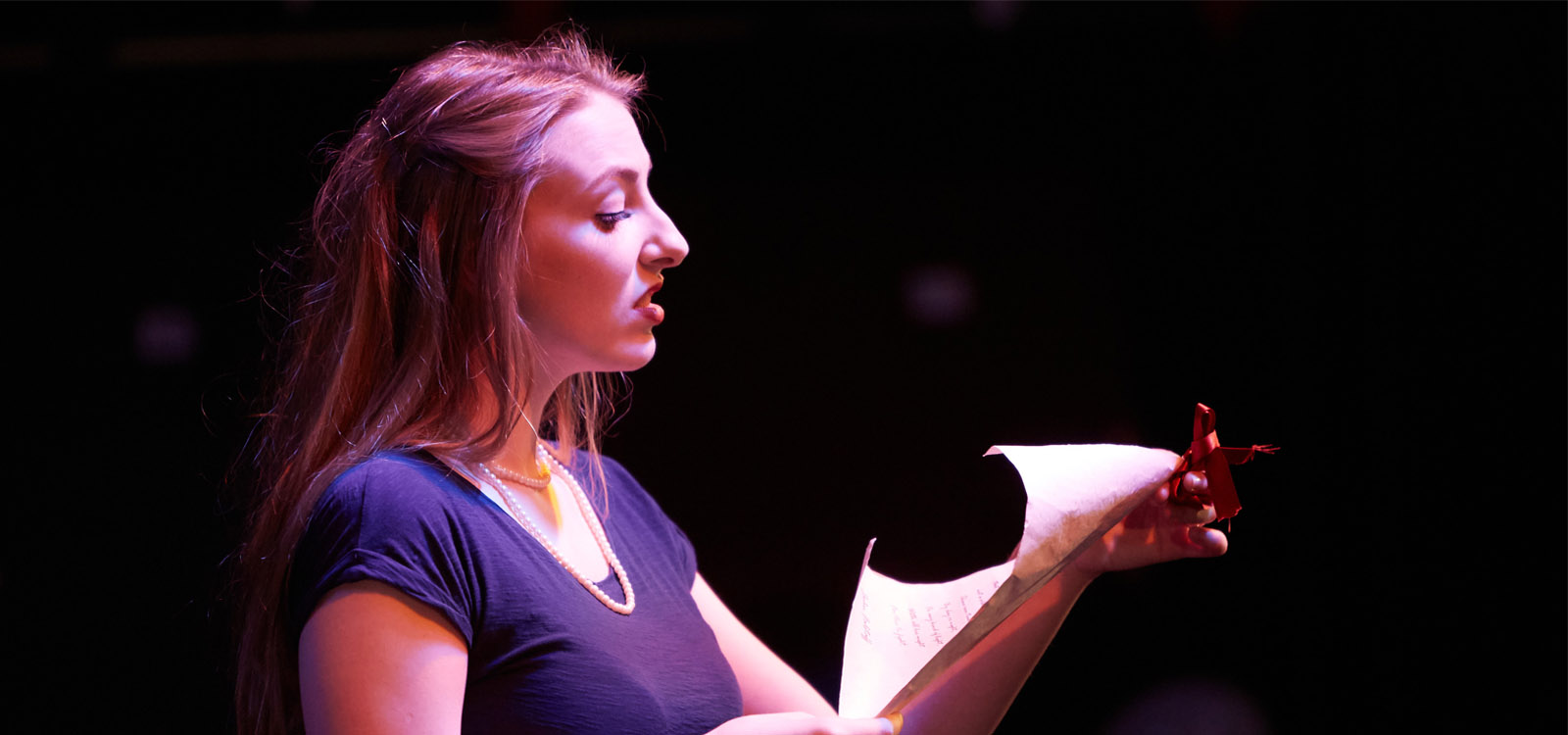 Female student reading from a script on stage 