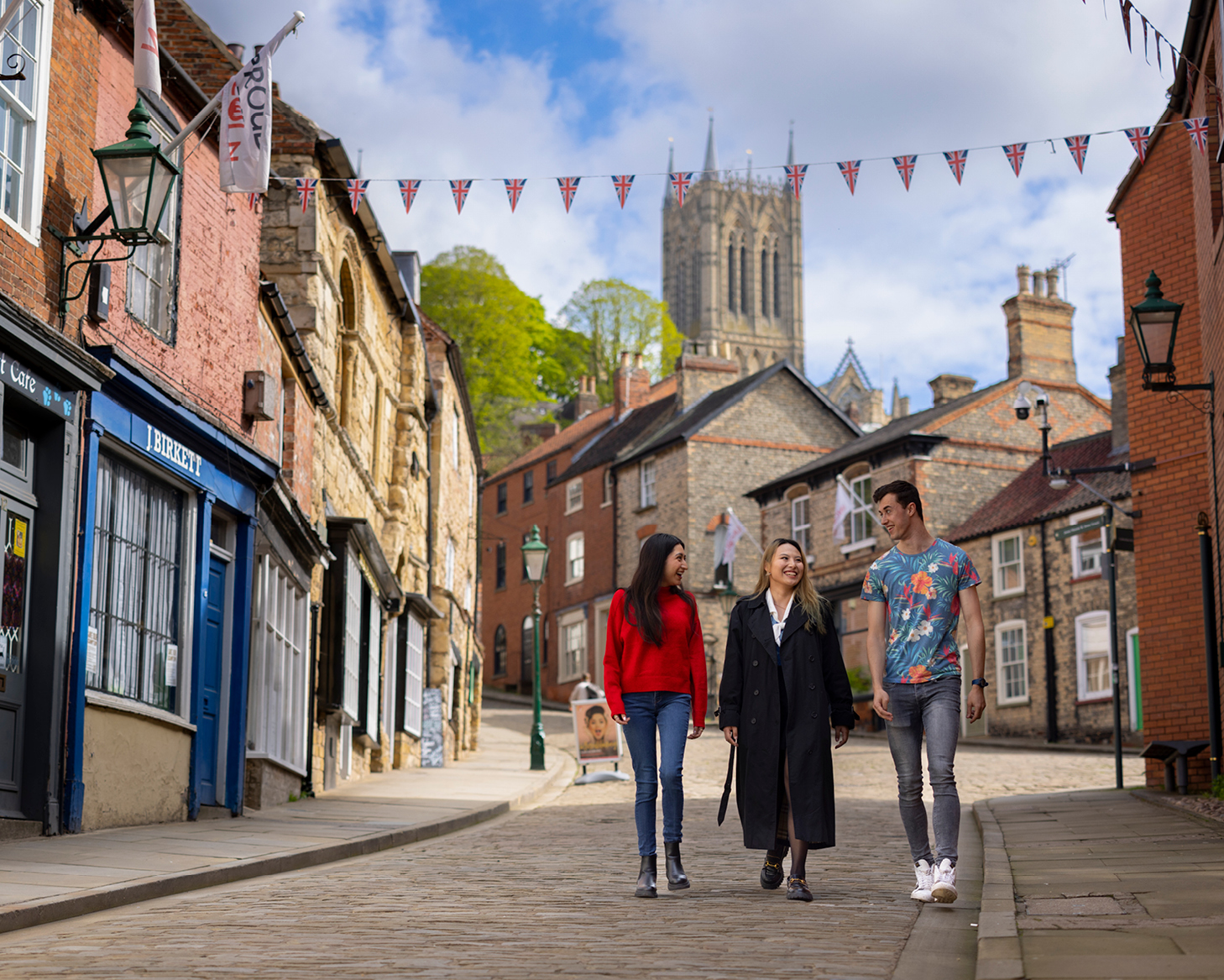 three students walking down steep hill with cathedral in the background