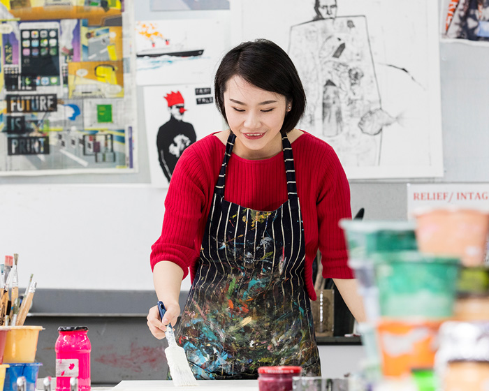 A student in a paint splattered apron painting