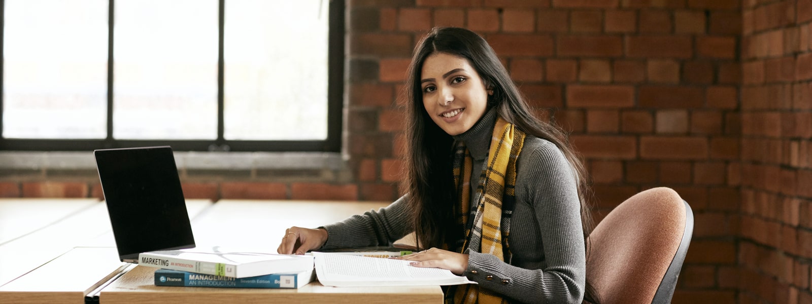 Student sitting at a desk with textbooks and laptop