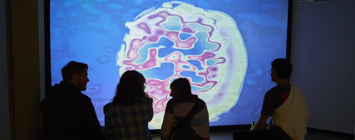 Students looking at a colourful artwork on a screen by Paige Whittaker