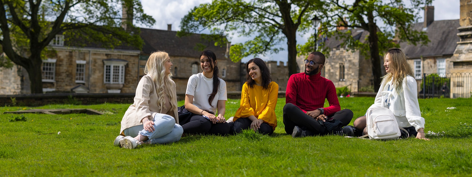 Students sitting together on grass at Lincoln Cathedral
