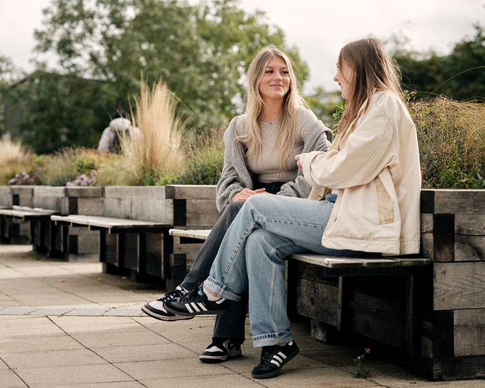 Two students sat chatting on campus