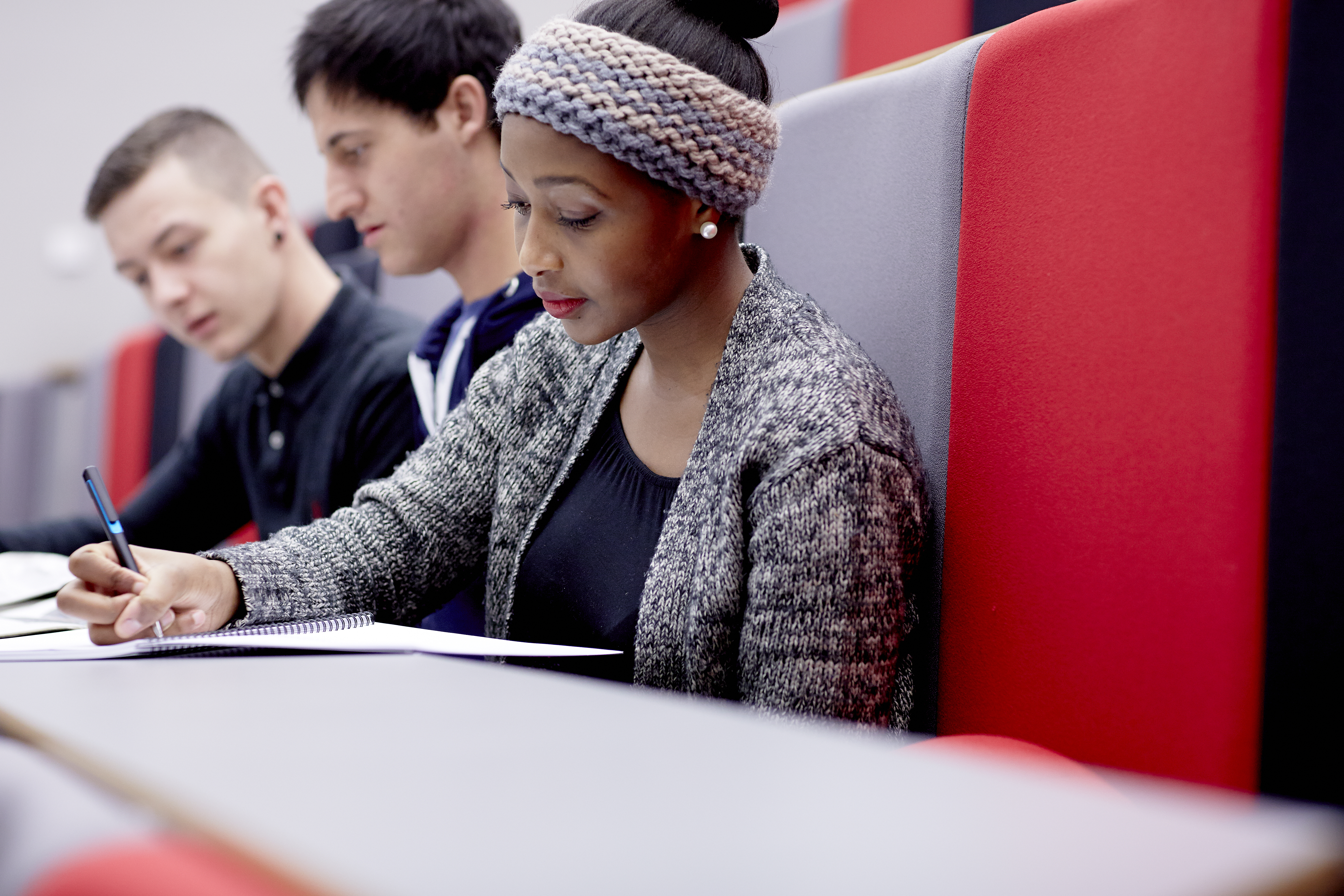 Student writing notes in a lecture.