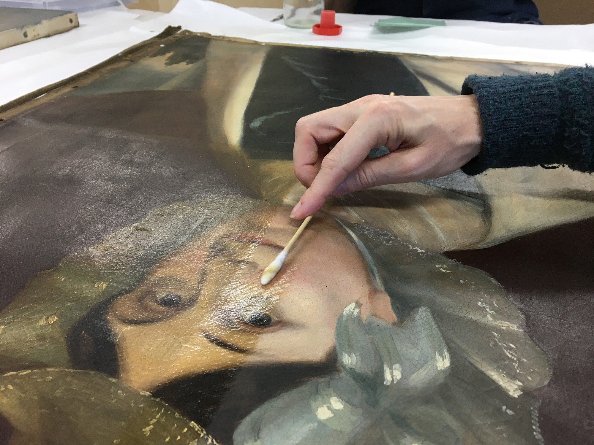 A portrait painting being restored