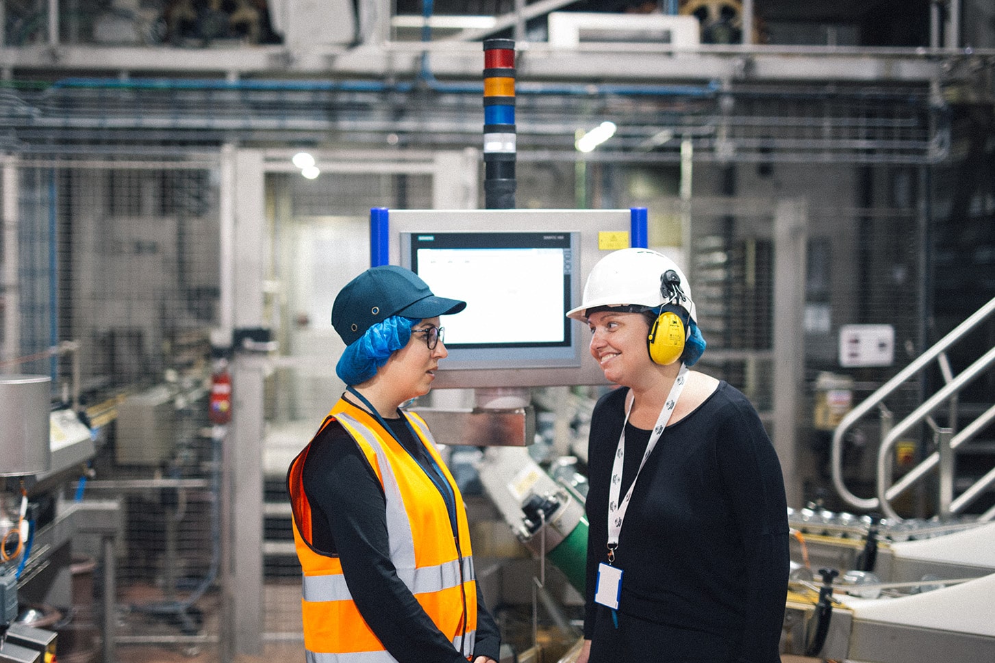 An academic and an employee wearing protective clothing in an industrial setting