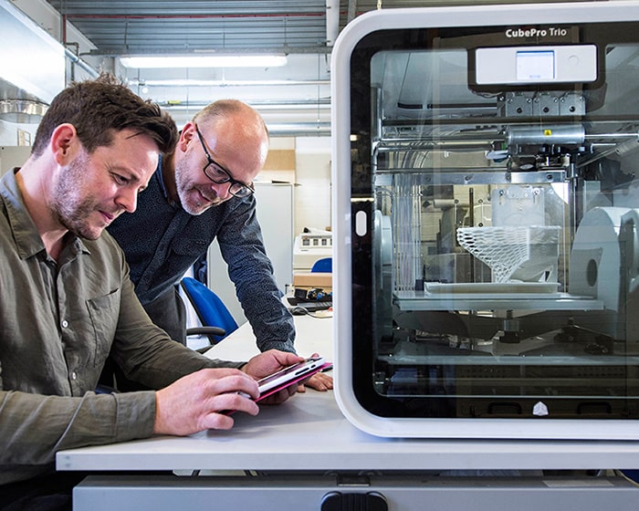 Two men looking at a 3D printer in action