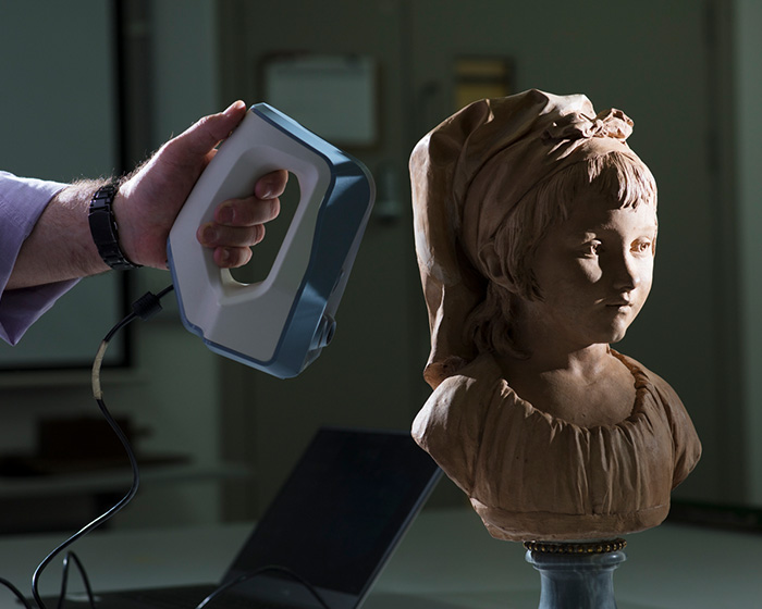 A mans hand taking a 3D scan of a statue