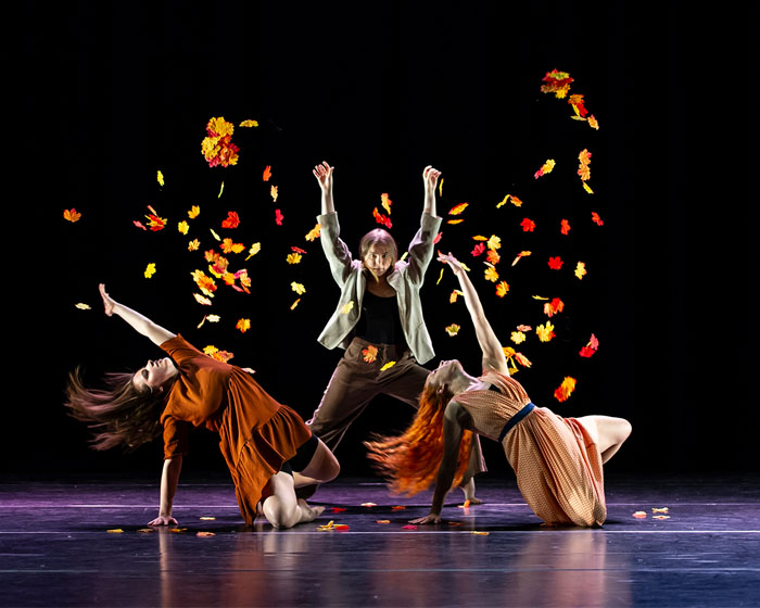 Students on stage throwing leaves in the air