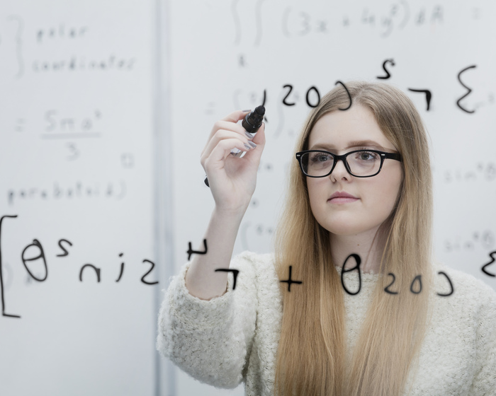 A student writing an equation on a board