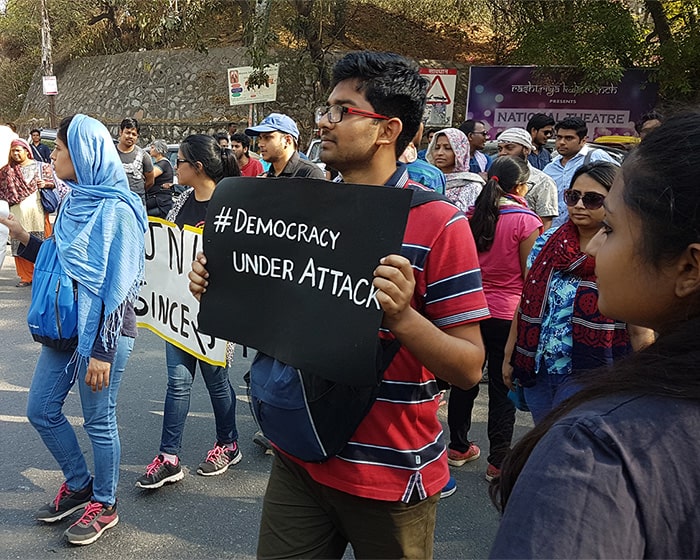 Group of protestors with the man in the foreground holding a sign