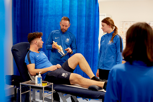 Students in a clinical setting receiving a demonstration from a lecturer