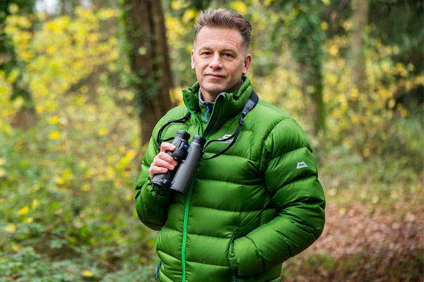 Chris Packham stood in a woodland with a green coat