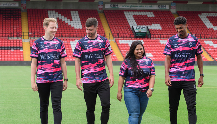 Students in football kits walking on a football pitch