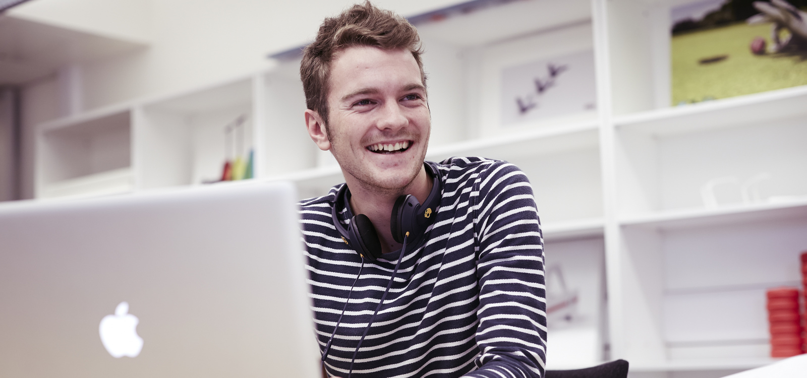 Male student smiling while working on a laptop
