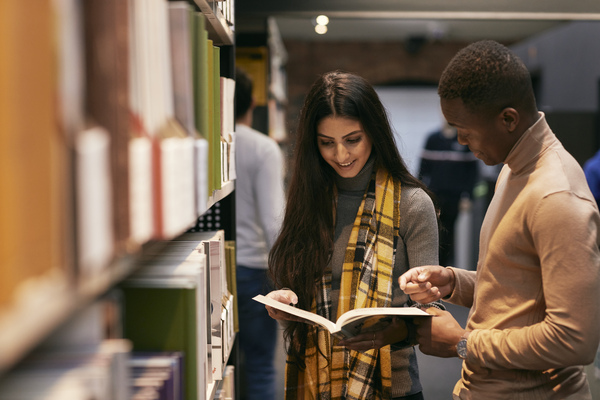 Two students in the library looking at a book