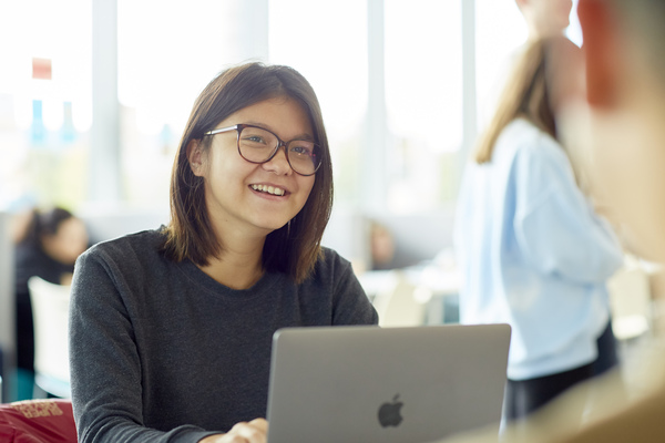 students smiling at the camera with the laptop on the table