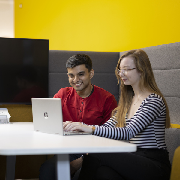 two students sitting together looking at a laptop