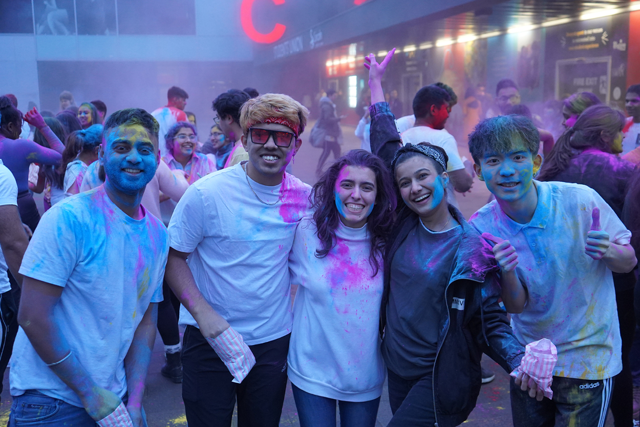 5 students at holi festival smiling at the camera