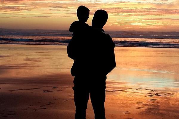 A father with his son on a beach at sunset