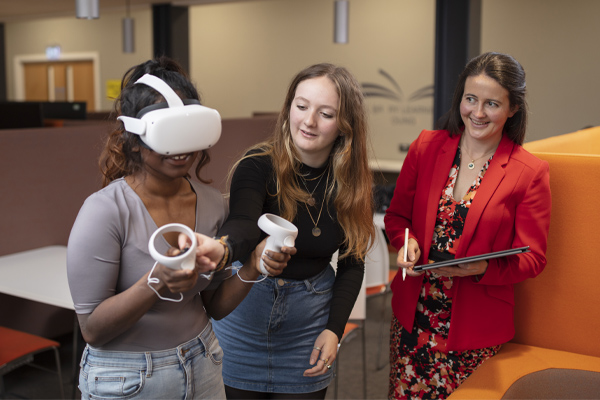 Two students using VR equipment under the guidance of an academic