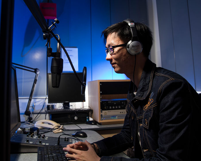 A student sitting at a microphone in a radio station